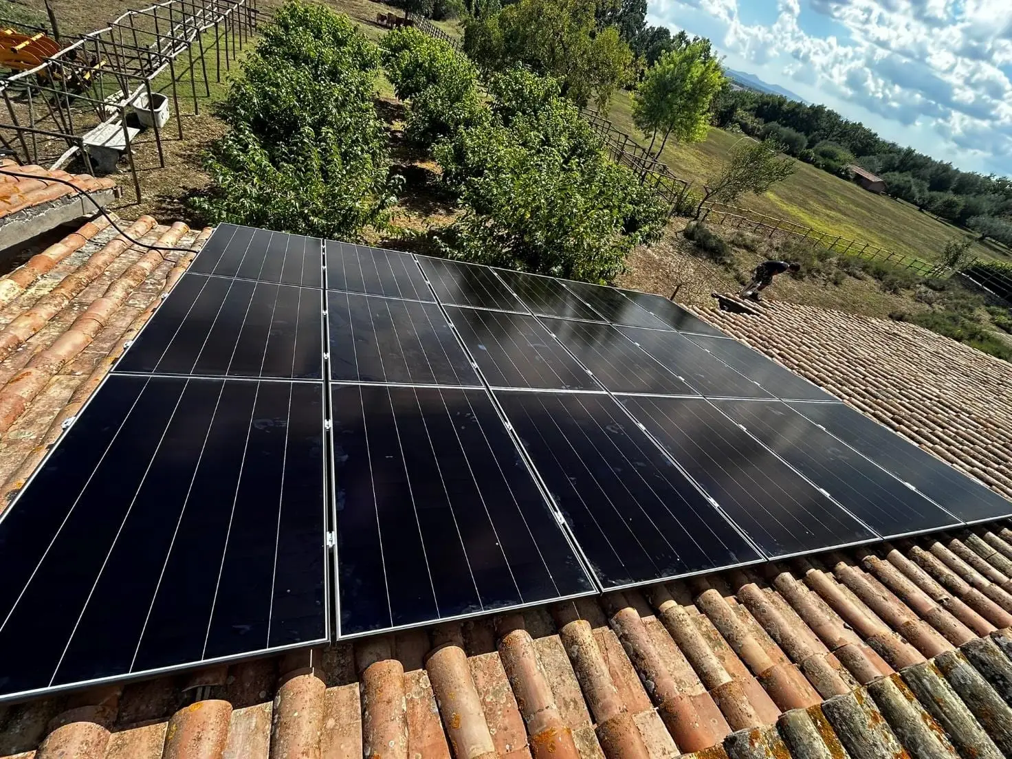 Moduli fotovoltaici su un tetto in coppi tra gli alberi