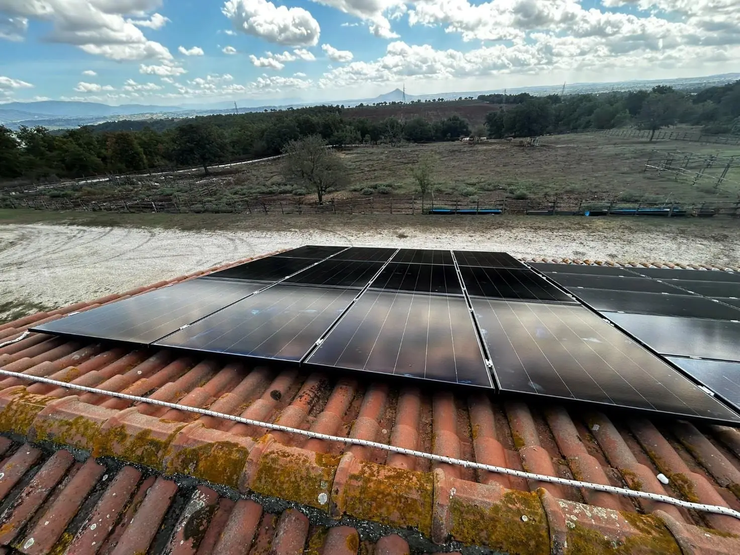 Impianto fotovoltaico aziendale su un tetto in coppi, con vista sul paesaggio